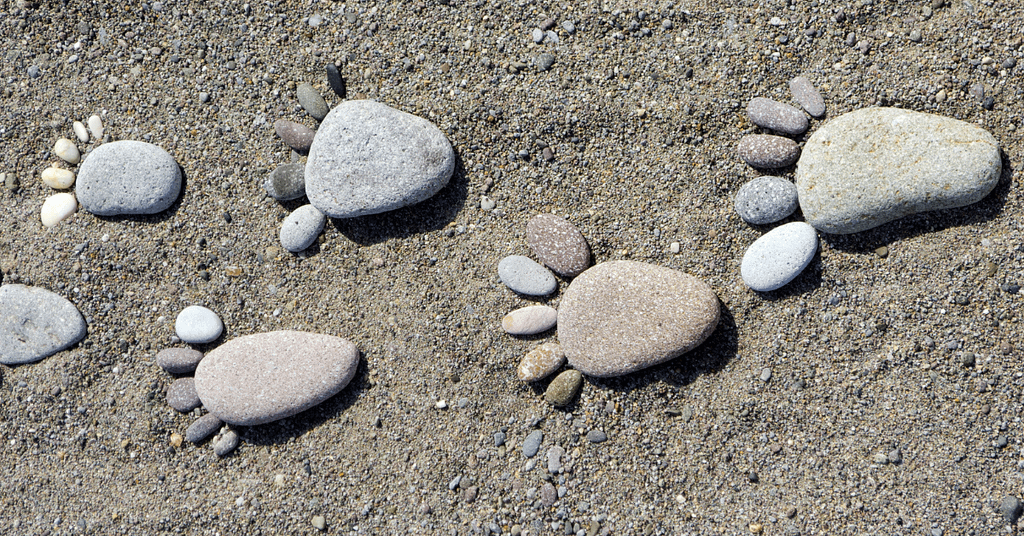 Pebbles arranged in the shape of footprints on sand
