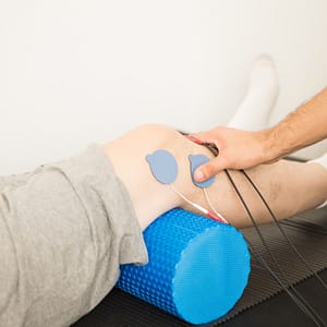 Physiotherapist applying TENS electrode pads on a patient’s knee to reduce pain and muscle tension related to flat feet and meniscus strain.